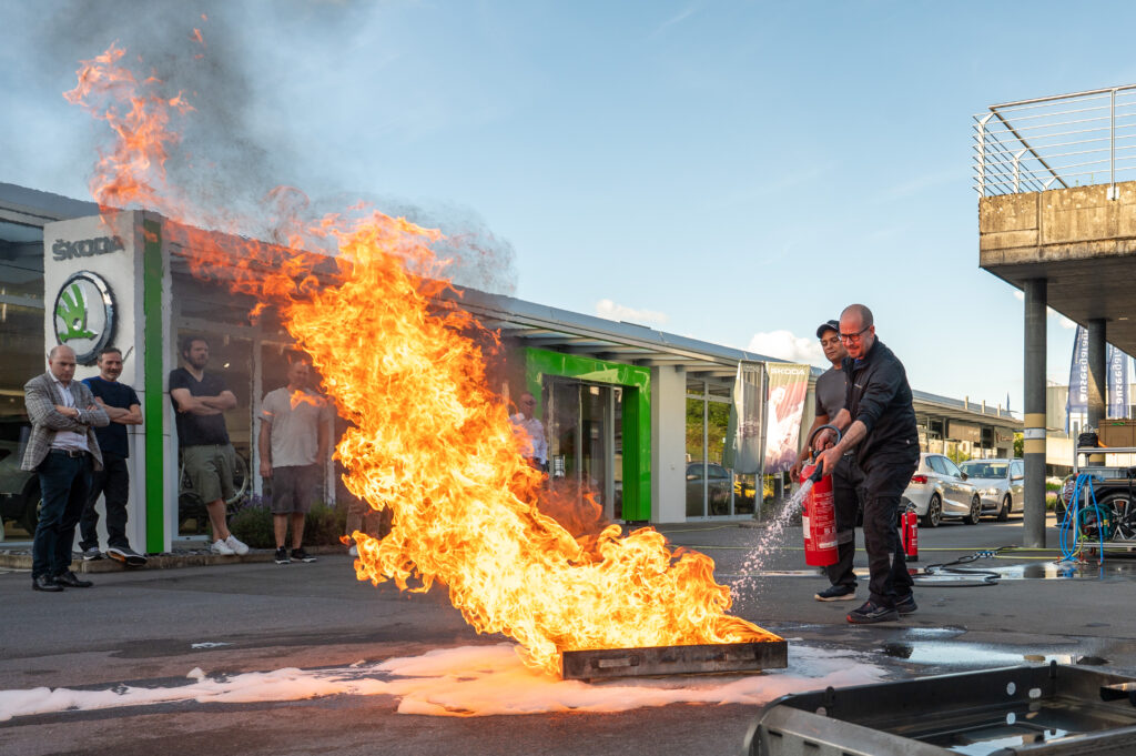eilnehmer löscht bei einer Brandschutzübung ein kontrolliertes Feuer mit einem Feuerlöscher